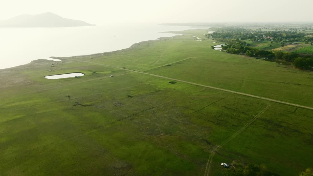 Aerial view shot of Landscape at the end of Pa Sak Jolasid Dam with green grass and water