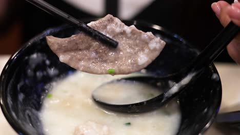 savoring a traditional dish with chopsticks and spoon