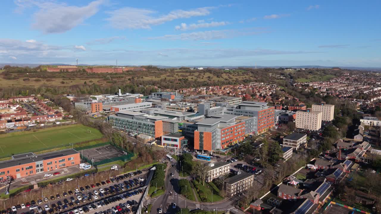 Drönarflygning över Queen Alexandra Hospital Portsmouth som närmar sig sjukhuset och visar hela området i starkt solsken på en klar dag med utsikt över kullarna och landsbygden bortom