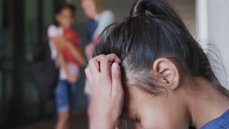 video of sad biracial girl taunted by two diverse girls in school corridor, copy space