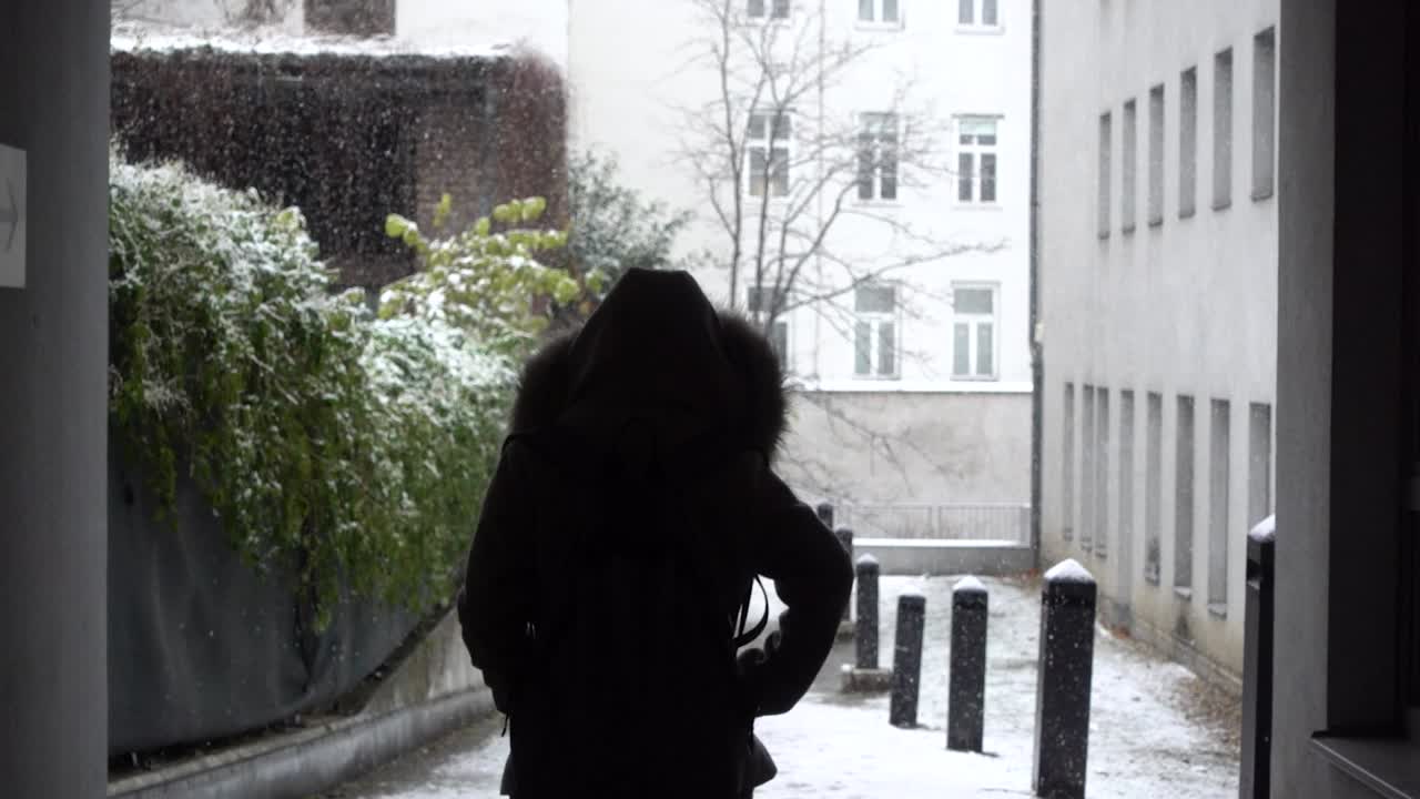 터널을 통해 눈 속으로 걸어가는 겨울 코트를 입은 여성의 실루엣