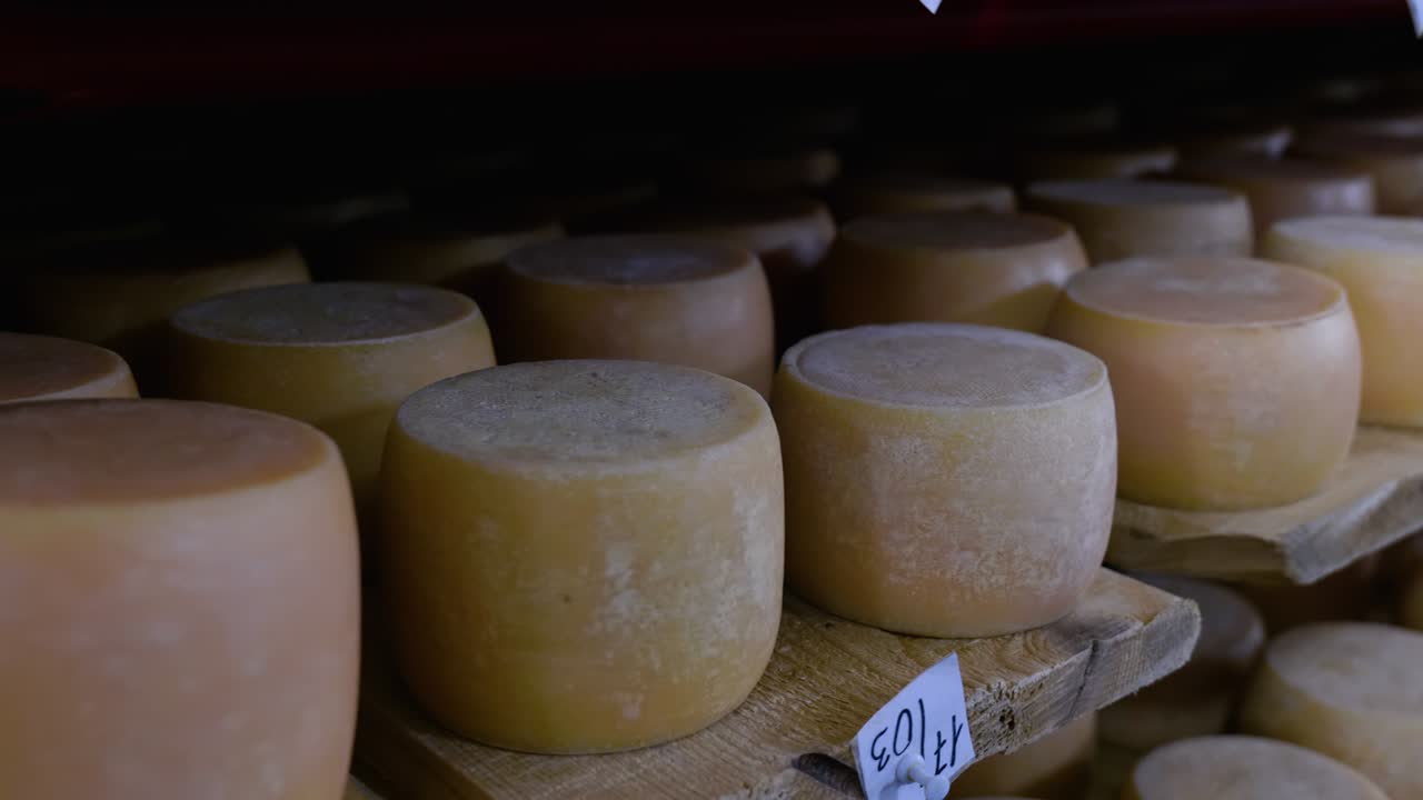 Vista de las hormas de queso parmesano madurando en los estantes de la bodega de la quesería.
