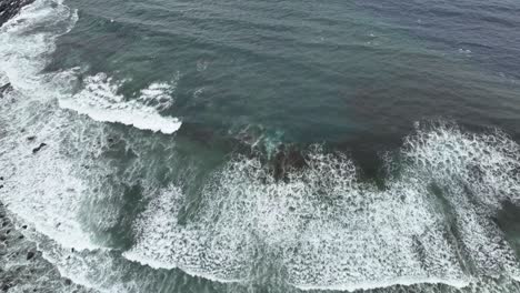 ocean waves rolling up on sandy beach in western norway - tilt up aerial from beach birdseye to revealing full coastal landscape ahead - alnes aalesund