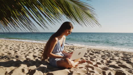woman working on laptop on a tropical beach