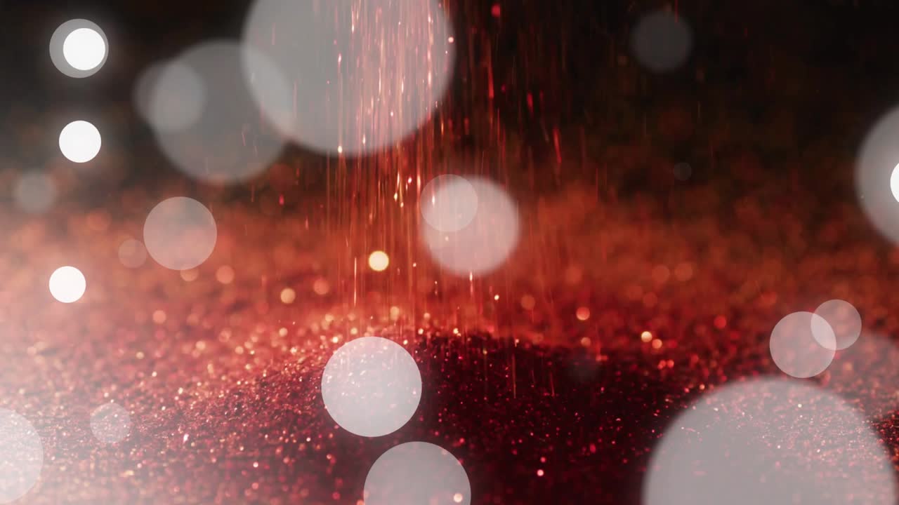 Red particle stream starting and falling, forming mound while sending sparkles and bokeh drifting