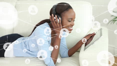 animation of network of connections with icons over african american woman using tablet