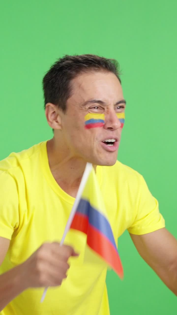 Man cheering for Colombia waving a national flag looking away