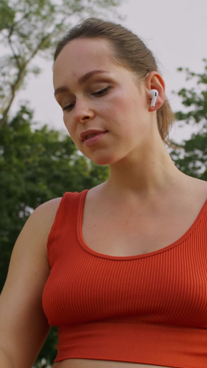 mujer en un parque escuchando música y usando un teléfono