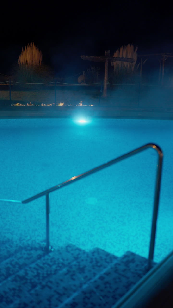 Illuminated Swimming Pool at Night with Steam Rising