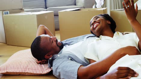 Smiling-couple-lying-on-floor-and-talking-in-living-room