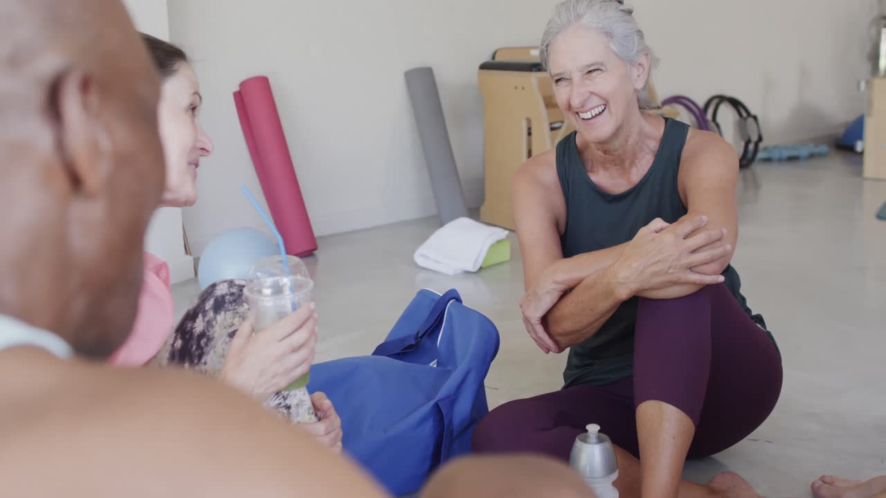 ancianos felices y diversos hablando con una entrenadora en clase de pilates, sin alteración, en cámara lenta