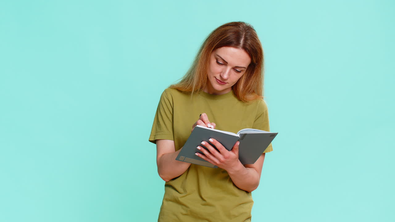 Donna che scrive su un quaderno, poi si ferma a pensare guardando in alto mentre pianifica il futuro o prende una decisione importante