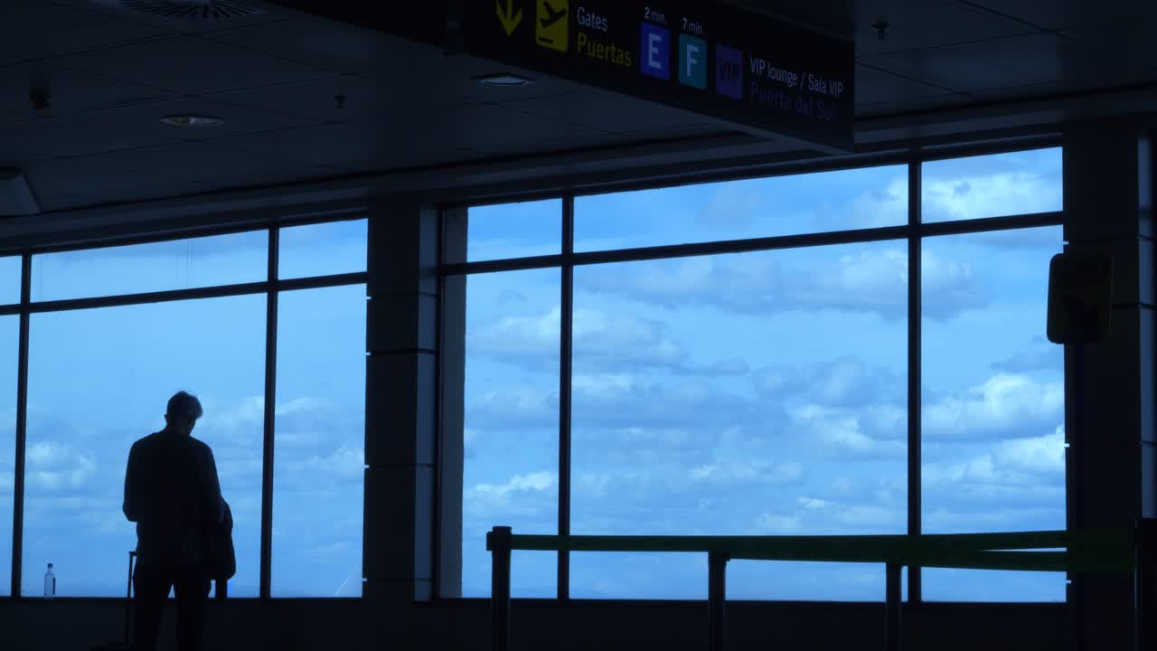 Silhouette di una persona in attesa vicino a una finestra in un terminal aeroportuale