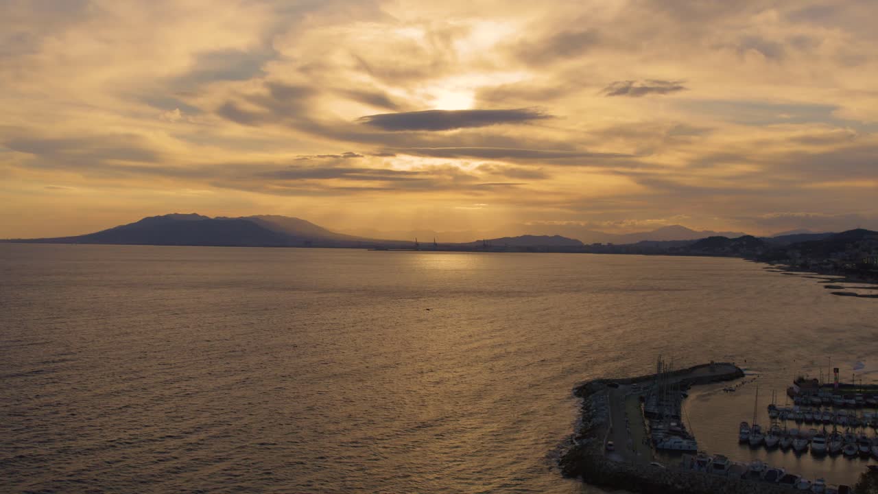 해가 지평선 아래로 지는 동안 해변 위의 하늘을 가로질러 다채로운 구름