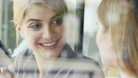 Dos-Mujeres-Usando-Una-Tableta-Digital-Bebiendo-Café-En-La-Cafetería