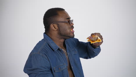 african man eating pizza. young african handsome man eating pizza isolated on grey background