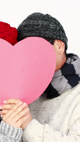 pareja asiática madura cubriendo su cara con un corazón de almohada