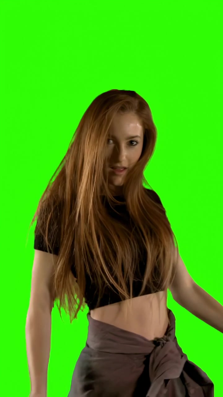 Pystyvideo: Tanssiva nainen saapuu käsivarren heilautuksella, yllään musta crop-toppi vihreällä taustalla.
