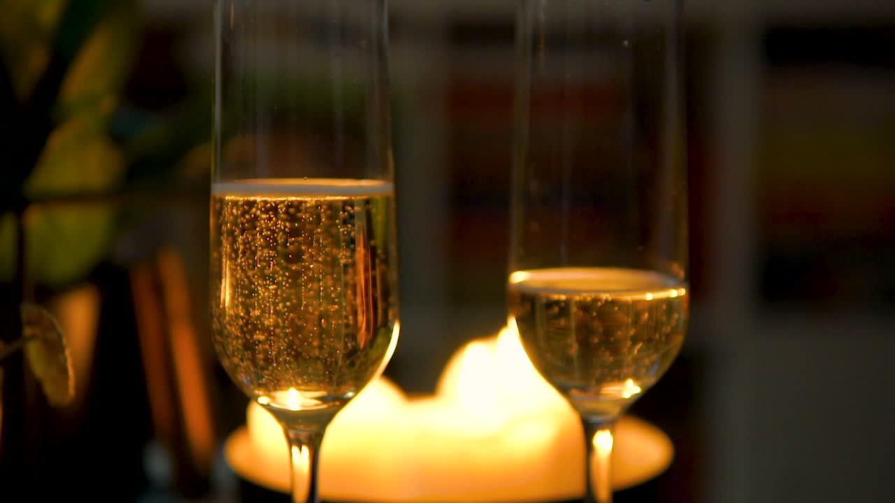 촛불이 켜진 저녁 식탁에 거품이 이는 샴페인이 반쯤 채워진 잔
