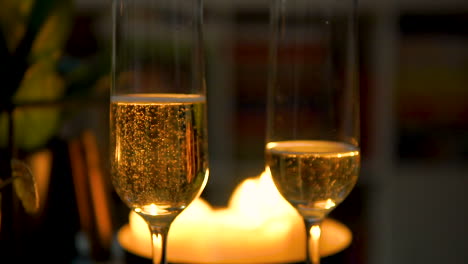 glasses half-filled with bubbly champagne on candlelit dinner table