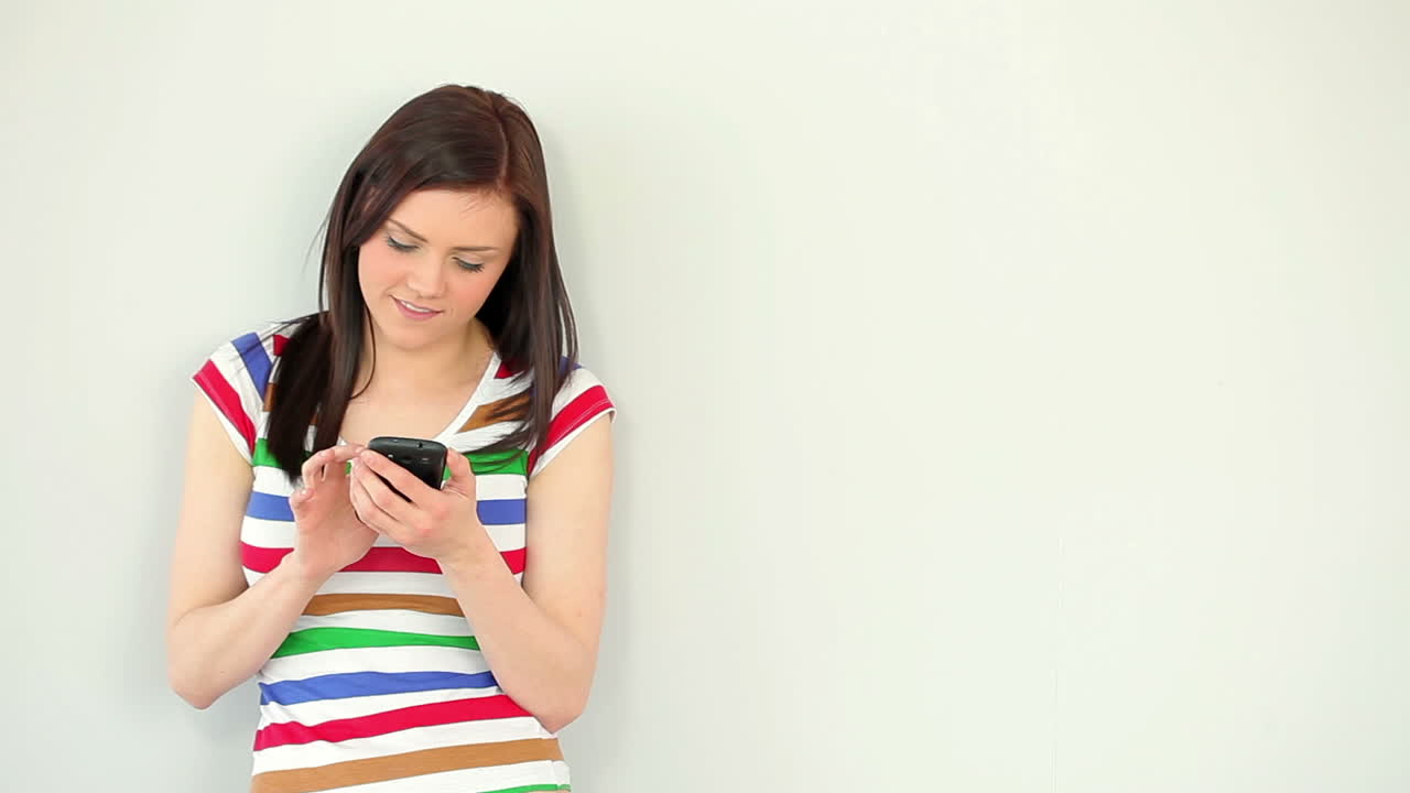 행복한 젊은 여성이 드폰으로 문자 메시지를 보내고 있습니다.