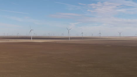 aerial push in towards massive wind farm surrounded by flat plains in north texas on a sunny day