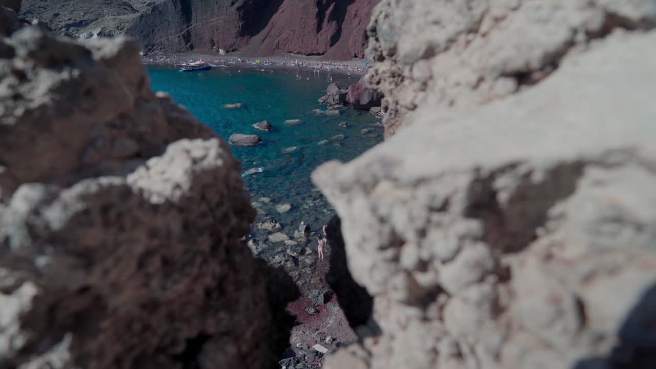 POV Red beach from between the rocky edge in Santorini
