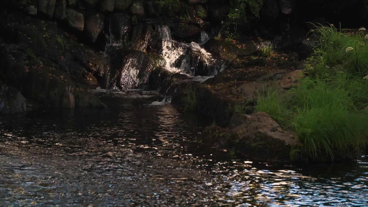 clara cascada de manantial que desemboca en un pequeño arroyo