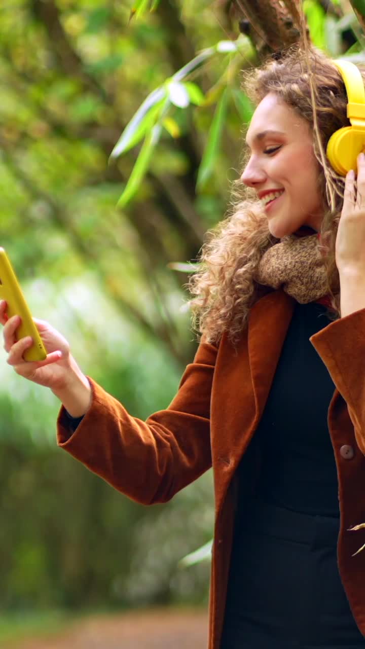 Woman taking a selfie in nature while listening to music with headphones