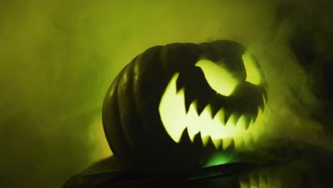 Video-of-halloween-carved-pumpkin-with-smoke-and-green-light-on-black-background