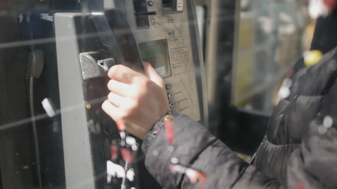 An unrecognizable girl ending a call hanging up the phone. The woman puts down the telephone receiver in a public phonebox putting down the payphone