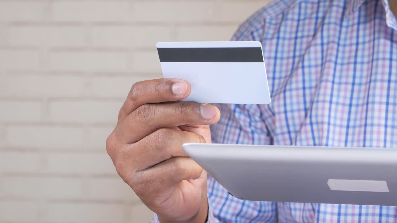 persona que utiliza una tableta y una tarjeta de crédito para el pago en línea