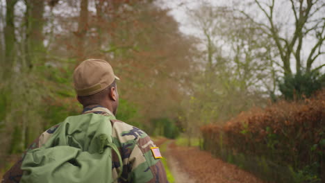 rear view of american soldier in uniform carrying kitbag returning home on leave