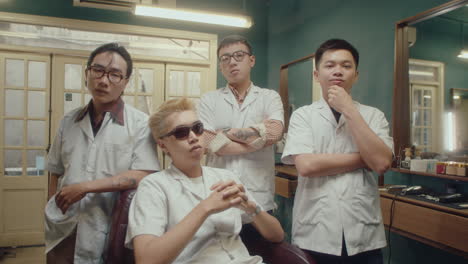 team of asian barbers posing on camera in retro barbershop