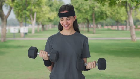 happy indian girl lifting heavy dumbbells