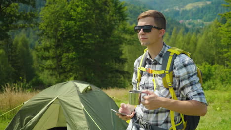 a young man with a backpack use a smartphone in the camping always in touch app for tourism