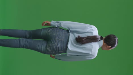 vista trasera de una mujer de negocios asiática caminando en el fondo de la pantalla verde en el estudio