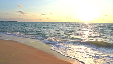 slow-motion waves wash up on a deserted tropical beach under a setting sun
