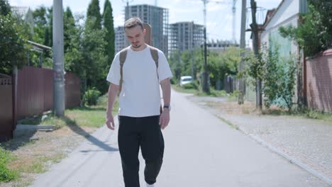 young man walking with guitar on street near forest