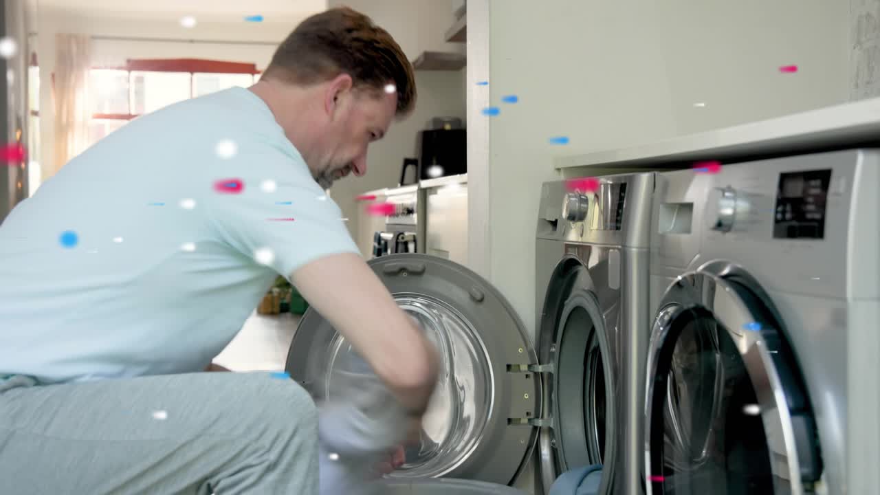 Mature man opening washer door loading clothes for laundry red or blue confetti floating around him