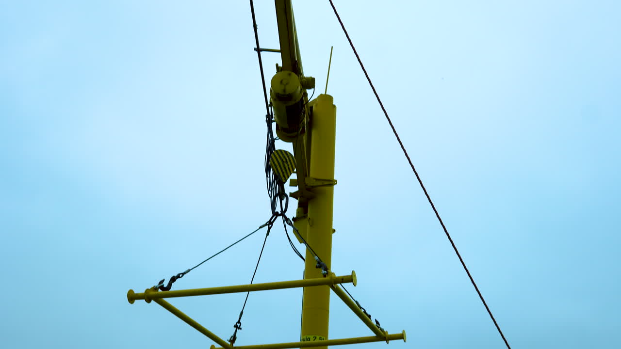 Yellow crane at the edge of the marina, raised crane frame hangs in the air