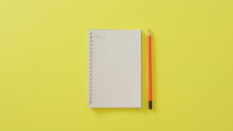 video of notebook with copy space and pencil on yellow background