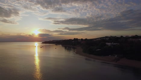 Costa-Con-Casas-Y-Puesta-De-Sol-Dorada-Sobre-El-Mar-Playa-Aérea-De-Trikorfo-Grecia