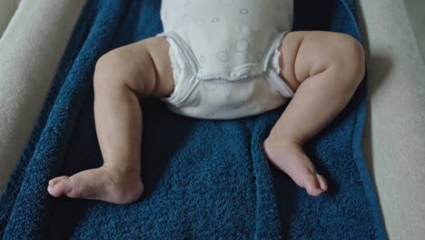 bebé recién nacido moviendo los pies en la toalla azul. de mano