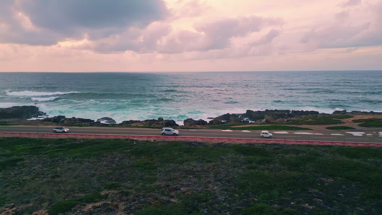 Coastal road stretching ocean coast washed by stormy turquoise waves drone view.