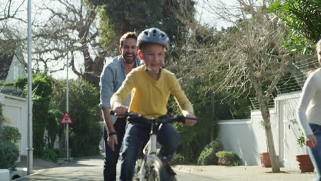 father teaching children to ride bikes