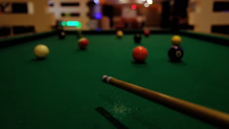 Person-is-playing-billiards,-hitting-white-ball-with-cue-into-pockets-on-billiard-table,-leisure-and-relaxing-activity-concept