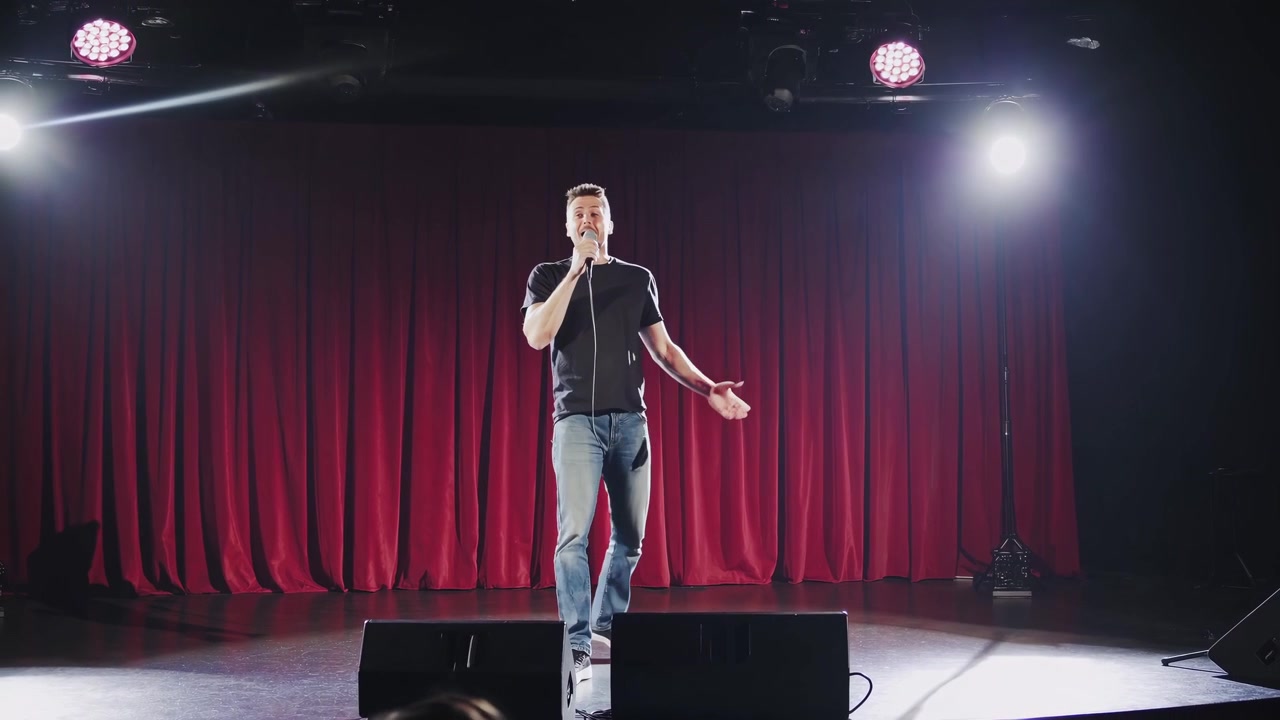 Kırmızı Perdelerle Sahnede Gösteri Yapan Stand-up Komedyeni