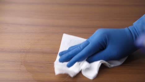 cleaning a wooden table with gloves