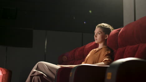 side view of blonde woman sitting in the cinema and watching a movie 1